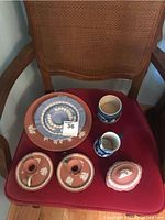 Full view of the set on a red chair showcasing all items including plates, candleholders, creamer, sugar bowl, and candy dish