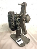 Side view of the antique Revere Eight 8mm film projector showing metal body and mechanical parts mounted on a rectangular base with a label number visible.