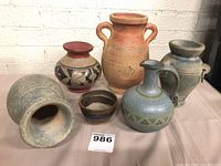 Overall group of six art pottery vessels showing varying shapes, sizes, and painted or carved decoration.
