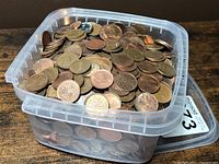 Clear plastic container filled with mixed Canadian and United States one cent coins. Coins show varying wear and patina.