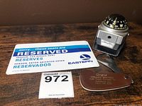 Photo showing the Eastern Airlines reserved placard, Texaco bottle opener with leather sheath, and car compass.