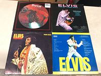 Four LP record albums including Meat Loaf picture disc and three Elvis Presley albums laid out on a white table surface.