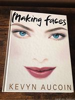 Front cover of the hardcover book titled 'Making Faces' by Kevyn Aucoin, featuring a stylized face with blue eyes and red lips