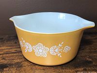 Front angled view of the harvest gold Pyrex casserole dish showing white floral pattern.