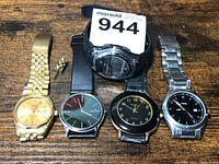 Lot showing five men's wristwatches together on wooden surface.