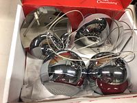 Photo of two chrome pendant lamps with hanging cables, shown inside a box with paper packaging.