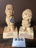 Photo showing both vintage Paula figurines on wooden surface, Dad and Mom figurines side by side with base inscriptions visible.