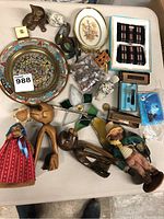 Overview of all vintage collectibles showing various small items, wooden figurines, dolls, decorative plates, and other accessories on white table