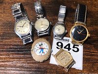 Collection of 6 vintage men's watches and a pocket watch showing diverse styles and conditions, including a black dial watch and a Mickey Mouse watch.