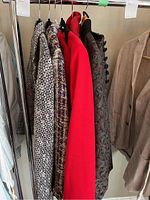 Seven ladies blazers hanging on rack showing different colors, patterns, and textures