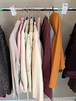 Row of ladies blazers and suits in various colors and fabrics on a rack.