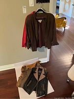 Overview of four jacket and vest items - dark brown suede jacket, white leather jacket, black leather vest with tan lapels, and patchwork tan and brown suede vest