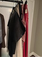 Skirts in black, beige, pink, and red hanging on a rack, showing textures and colors.