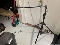 Full view of the black metal light stand with tripod base and horizontal extension arm attached at the top.