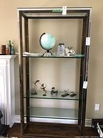 Assembled shelving unit with three installed glass shelves and display items