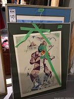 First framed print showing stylized violinist under glass with green tape