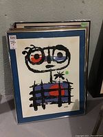 Abstract figurative print with black linework, red and blue accents, signed 'Miró', in a silver metal frame