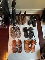 Full lot photo showing seven pairs of ladies shoes including Hunter rubber boots, brown ankle boots, black heeled shoes, and sandals.