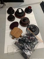 Overhead view of nine wooden display bases in various diameters, plus a clear plastic bag filled with assorted plate stands