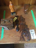 All wood pieces arranged on wood surface showing variety of items including figurines, box, spoon, coasters, and carvings.