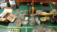 Top view of various glass, wood, and metal candle holders plus candles and accessories on green table.