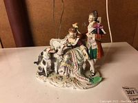 Front and side view of porcelain figurine showing detailed design, colors, and figures