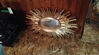 Overall view of mid-century modern sunburst mirror with wooden rays and oval mirror center