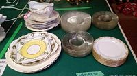 Overview of assorted side plates arranged on table including decorative porcelain plates, glass plates, and a white gravy boat.