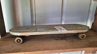 Side angle of the vintage wooden skateboard with light blue deck and Roller Derby wheels.
