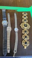 Four vintage ladies watches laid out on wooden surface, showing their faces and bands.