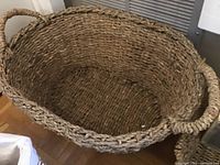Large oval woven basket with handles made from natural fibers.