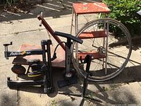 Overview of lot showing vintage metal folding step stool, wooden cart with wheels and handle, bicycle wheels, CCM hand air pump, and bicycle foot pedal accessory.