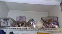 Wide view of three containers on a wire shelf holding various sewing and crafting supplies including buttons and thread spools.