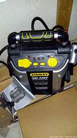 Front view of the Stanley 500 Amp jump starter with compressor and attached instruction manual.