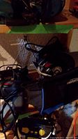Power tools and tool bag arranged on a wooden surface, showing parts of an electric saw with dust bag.