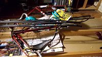 Red steel bicycle frame leaning against wall with coiled teal cable locks draped over the top tube.