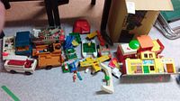 Overview of most toys laid on floor including trucks, plane, figures, and a barbershop playset