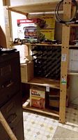 Front view of the wood shelving unit showing multiple wooden shelves and some boxed items on the floor and shelves. Unit is tall with vertical support beams.
