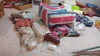 Photo shows multiple bags of wool yarn in cream, rust, and other colors on carpet with a striped bag nearby