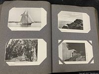 Open album showing black and white real photo postcards of coastal scenes, boats, and wooded road.
