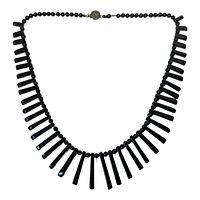 Full view of black jet glass necklace with alternating round beads and elongated tapered pendants, closed in a circular shape.