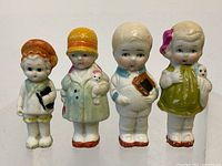 Front view of the four porcelain child figurines showing color and details