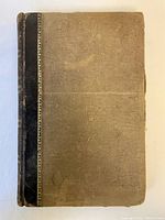 Front cover of the book showing textured cloth cover with a leather spine, faded and worn.