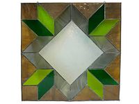 Front view of the large, square stained glass panel showing central diamond shape in clear textured glass and green leaf shapes around it.