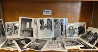 Loose black and white photographs spread on a wooden surface, showing urban and candid scenes.