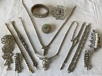 Top view of the full collection of antique rhinestone jewelry laid out on white background.