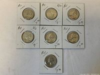 Seven 90% silver Washington quarters in cardboard holders, showing overall grouping and condition.