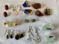 Full view of lot showing all pairs of earrings made of stone and sea glass in various colors and designs