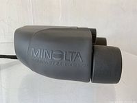 Side view of Minolta Compact EZ 8x21 binoculars showing brand and model details.