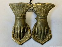 Top-down view showing both bronze hand clips with detailed cuffs and shield-shaped bases.